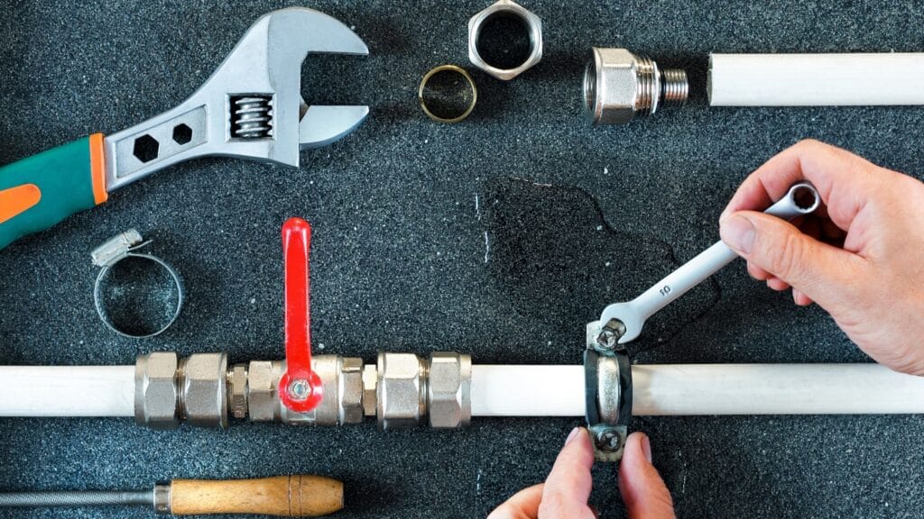 Plumber repairing a pipe valve with an adjustable wrench in Brandon