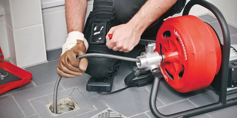 Plumber using a drain-cleaning machine in Brandon