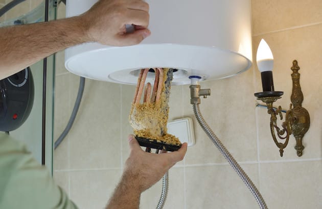 Technician removing mineral buildup from a water heater in Brandon