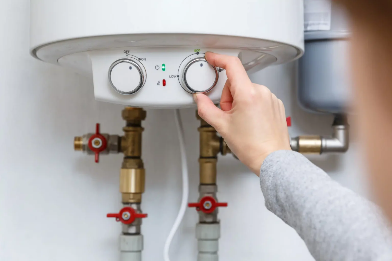 Homeowner adjusting the temperature controls on a water heater in Brandon